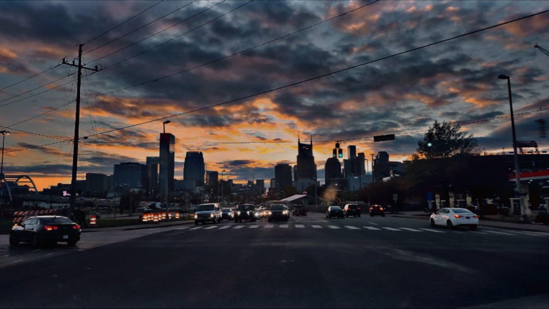 City skyline silhouette against a dramatic sunset sky with clouds and vibrant colors.